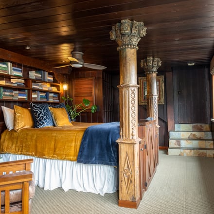 Ornate bedroom suite with carved columns and golden linens